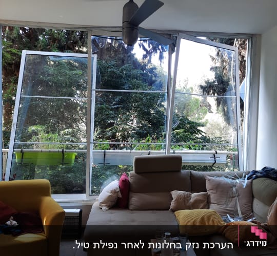 סלון עם ספה, חלונות פתוחים ועצים בחוץ